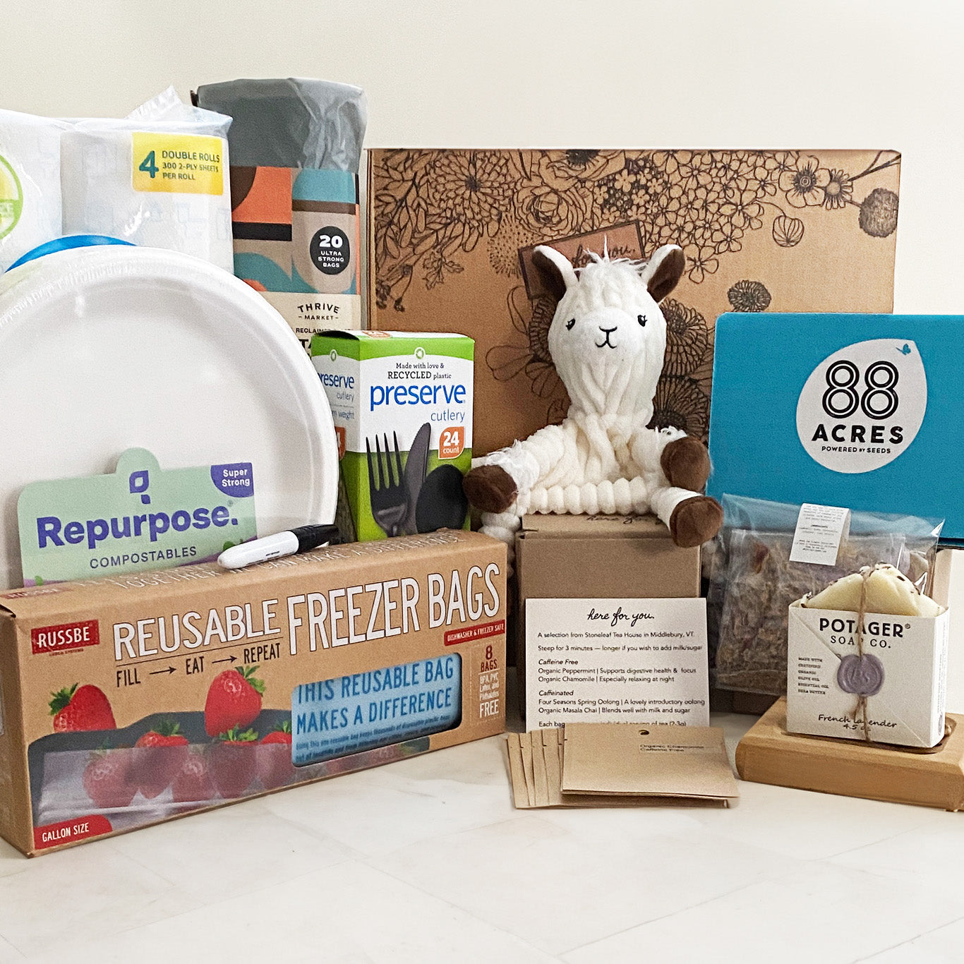 This **Here For You** care package is a **thoughtful and practical support box**, ideal for those navigating **birth, adoption, or major life transitions**. It includes **eco-friendly disposable plates, utensils, and paper towels**, **reusable freezer bags**, **snacks from 88 Acres**, **a soft llama plush**, **artisan soap**, and **herbal tea**. Designed for convenience and comfort, this package helps ease daily burdens while offering warmth and encouragement.