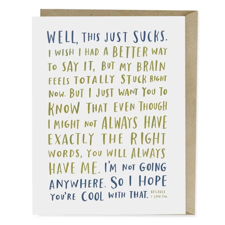 A sympathy card with a handwritten-style message reads, *"WELL, THIS JUST SUCKS."* in bold lettering. The heartfelt message acknowledges difficulty in finding the right words but reassures the recipient of unwavering support and presence. The text is in blue and olive green tones, creating a warm, personal touch. The card comes with a brown kraft envelope, making it a thoughtful and honest way to show support during tough times.