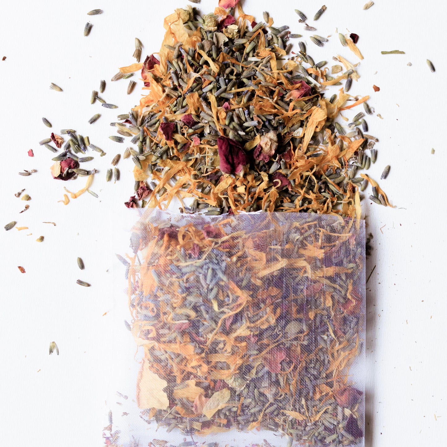 This image showcases a **herbal bath tea sachet** filled with a blend of **dried flowers and herbs**, including **lavender, calendula, and rose petals.** Some of the loose herbs are scattered around the sachet, highlighting its natural ingredients. This **aromatic and soothing bath soak** is designed to provide a **relaxing and therapeutic** experience, perfect for **self-care, stress relief, and skincare rituals.**