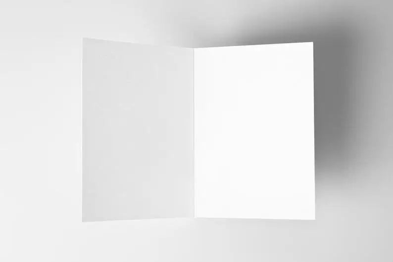 This image features a blank, open greeting card with a clean white interior, set against a neutral background. The card is positioned at an angle, showing both the left and right inner pages. It serves as a versatile canvas for handwritten messages, printed text, or creative designs, making it suitable for a variety of occasions.