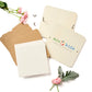 A flower press kit by Eco-Kids includes wooden covers, cardboard layers, blank paper sheets, and metal bolts for assembly. Surrounded by pink flowers and leaves, it encourages kids to press and preserve plants naturally.