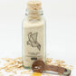 Bottle of oatmeal milk and honey foaming bath salts with a wooden scoop and oats on a white background