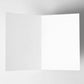 This image features a blank, open greeting card with a clean white interior, set against a neutral background. The card is positioned at an angle, showing both the left and right inner pages. It serves as a versatile canvas for handwritten messages, printed text, or creative designs, making it suitable for a variety of occasions.