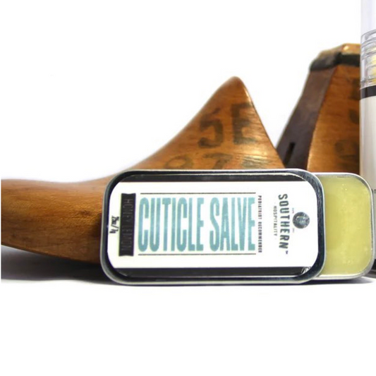 Open tin of Southern Hospitality Cuticle Salve in front of wooden shoe form, showing off its creamy yellow balm.