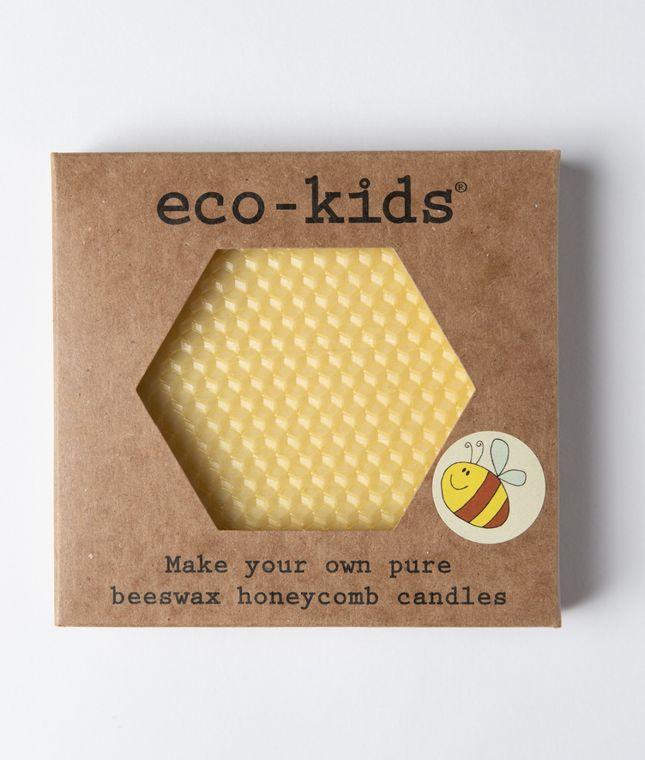 This image features an **eco-kids® Beeswax Honeycomb Candle Kit**, designed for crafting **pure beeswax candles**. The packaging has a **hexagonal cutout**, revealing the **natural honeycomb-textured beeswax sheets** inside. A small illustration of a **smiling bee** adds a playful touch. The **eco-friendly kit** encourages hands-on creativity, making it a **fun and sustainable activity** for kids and adults alike.